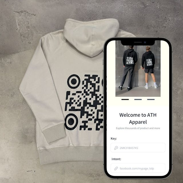 A person holding a phone with a user interface on the screen in front of a hoodie with a QR code