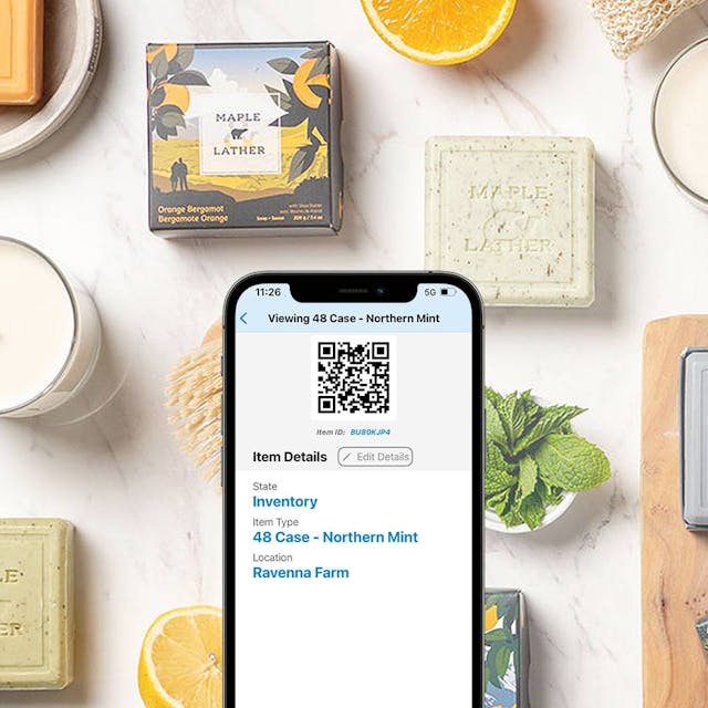 A phone showing a QR code with fancy soaps and plants in the background